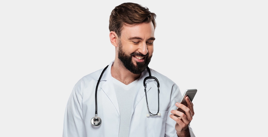 Ein Arzt schaut auf sein Smartphone und lächelt.